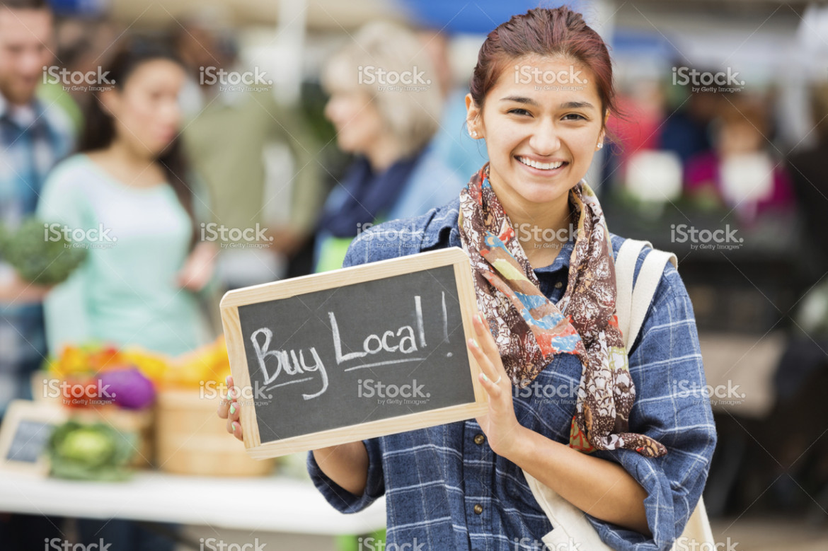 stock-photo-37466286-pretty-woman-holding-buy-local-sign-at-local-farmers-market.jpg